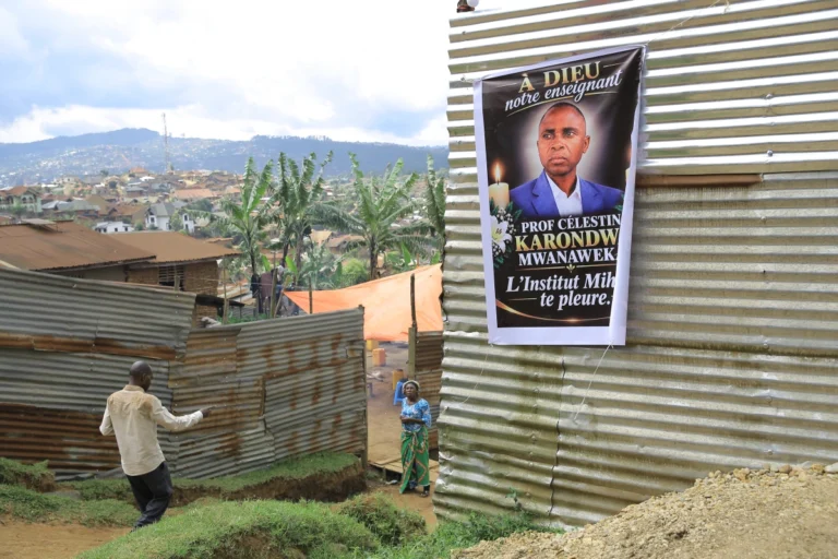 Mourners gather near a banner honoring Marie-Célestin Karondwa in Butembo